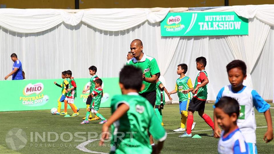 Kurniawan Dwi Yuliyanto saat memberikan arahan kepada ratusan anak dalam acara Milo Football Clinic. - INDOSPORT